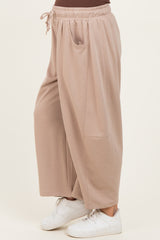 woman wearing beige maternity wide-leg pants with side pockets and an elastic waistband, styled with white sneakers