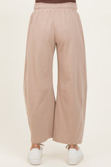 woman wearing light brown maternity wide-leg pants, viewed from the back with an elastic waistband and casual white sneakers
