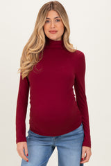 woman wearing a burgundy maternity turtleneck top and showing her baby bump with a relaxed fit and long sleeves
