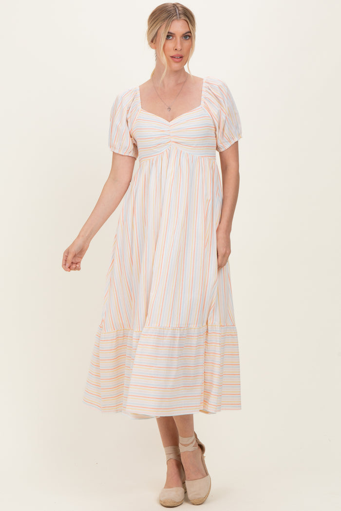woman wearing a white striped maxi dress with puff sleeves and a tiered hemline