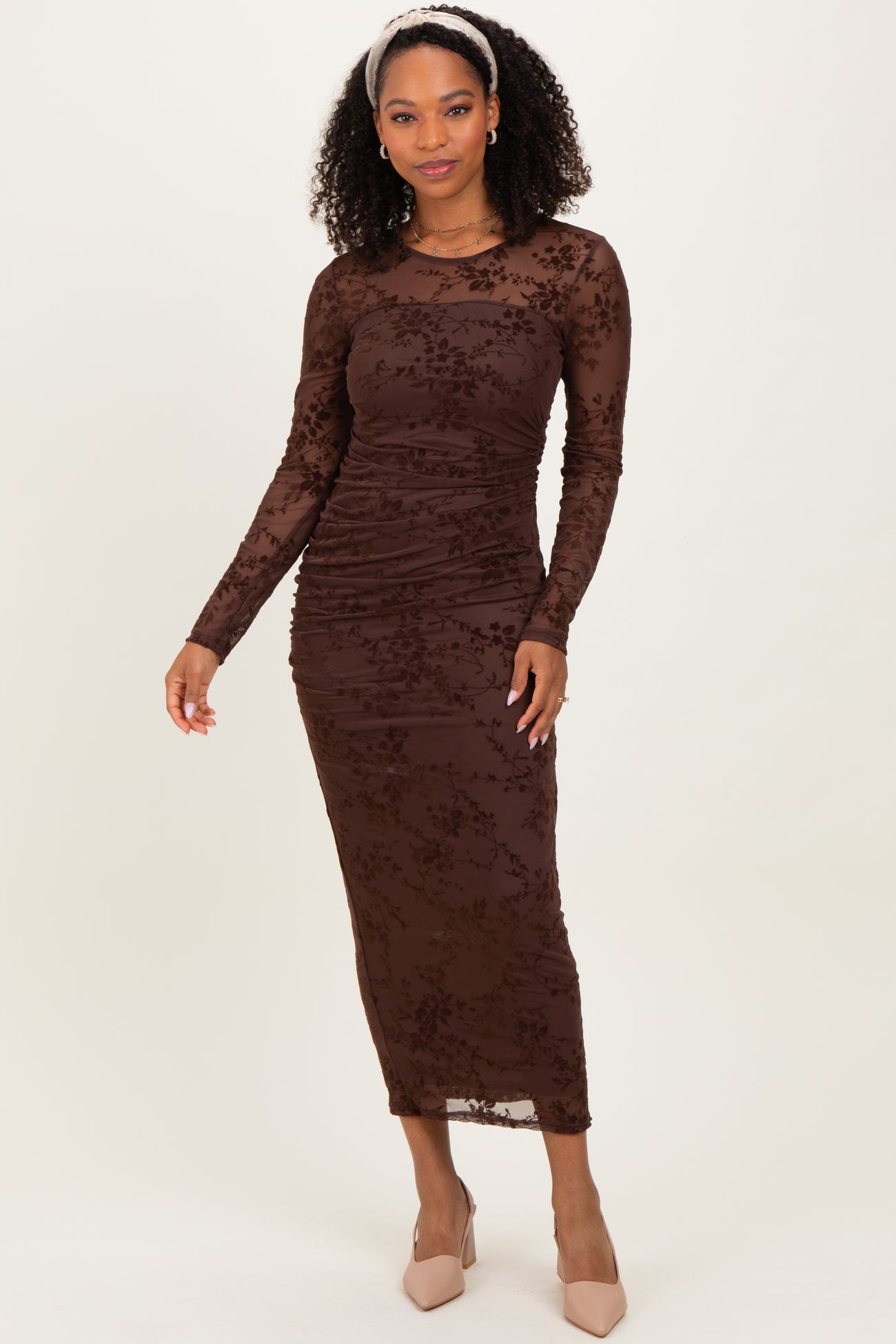 woman wearing a brown long sleeve ruched dress with floral lace details and heels