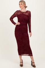 woman wearing a burgundy long sleeve bodycon dress with floral lace details and a fitted silhouette