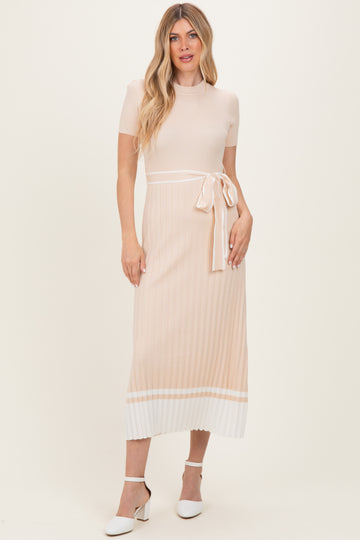 woman wearing a beige ribbed midi dress with a belt and white striped hem detail, paired with white heels