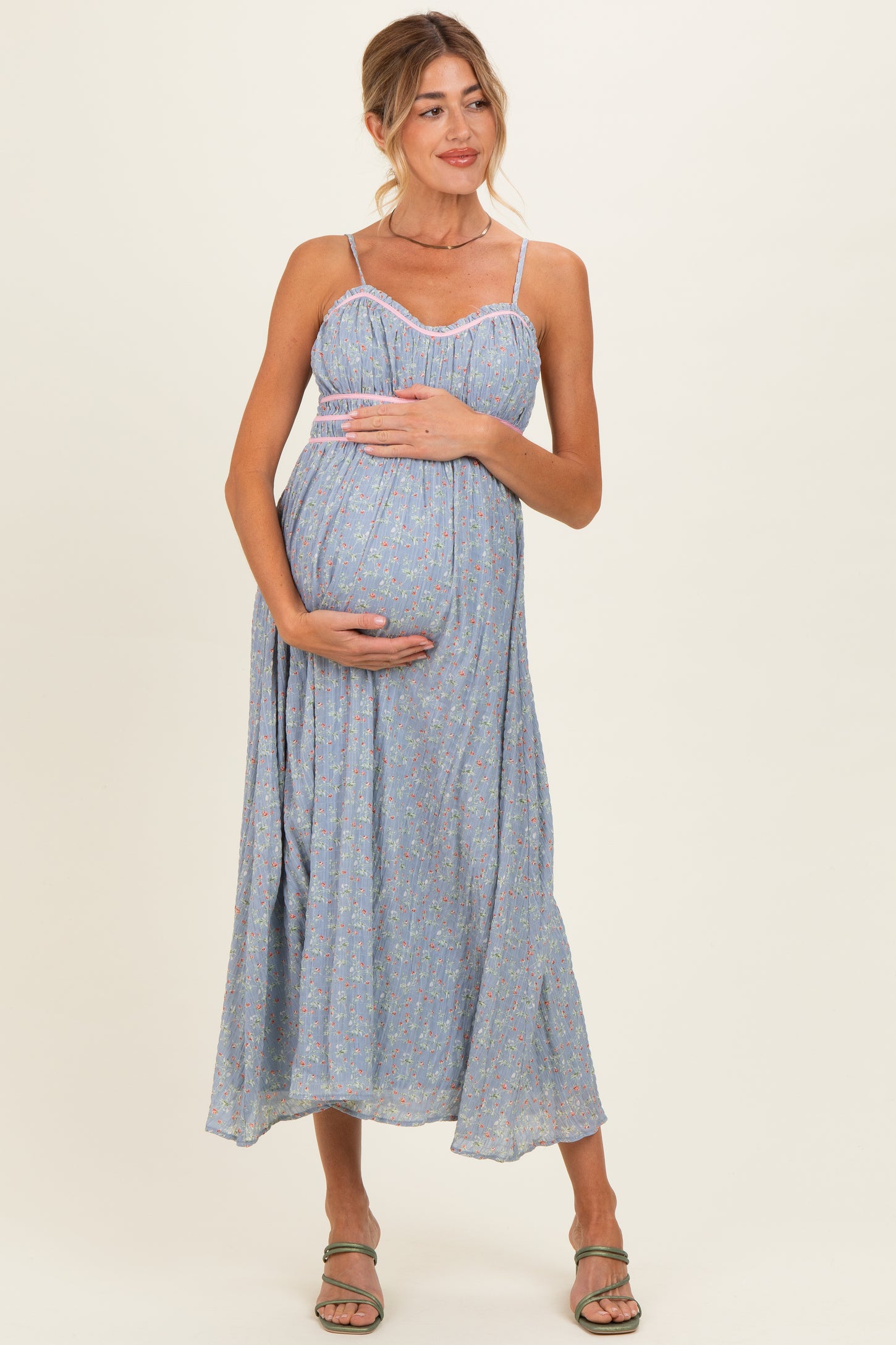 woman wearing a light blue floral maternity maxi dress, holding her baby bump