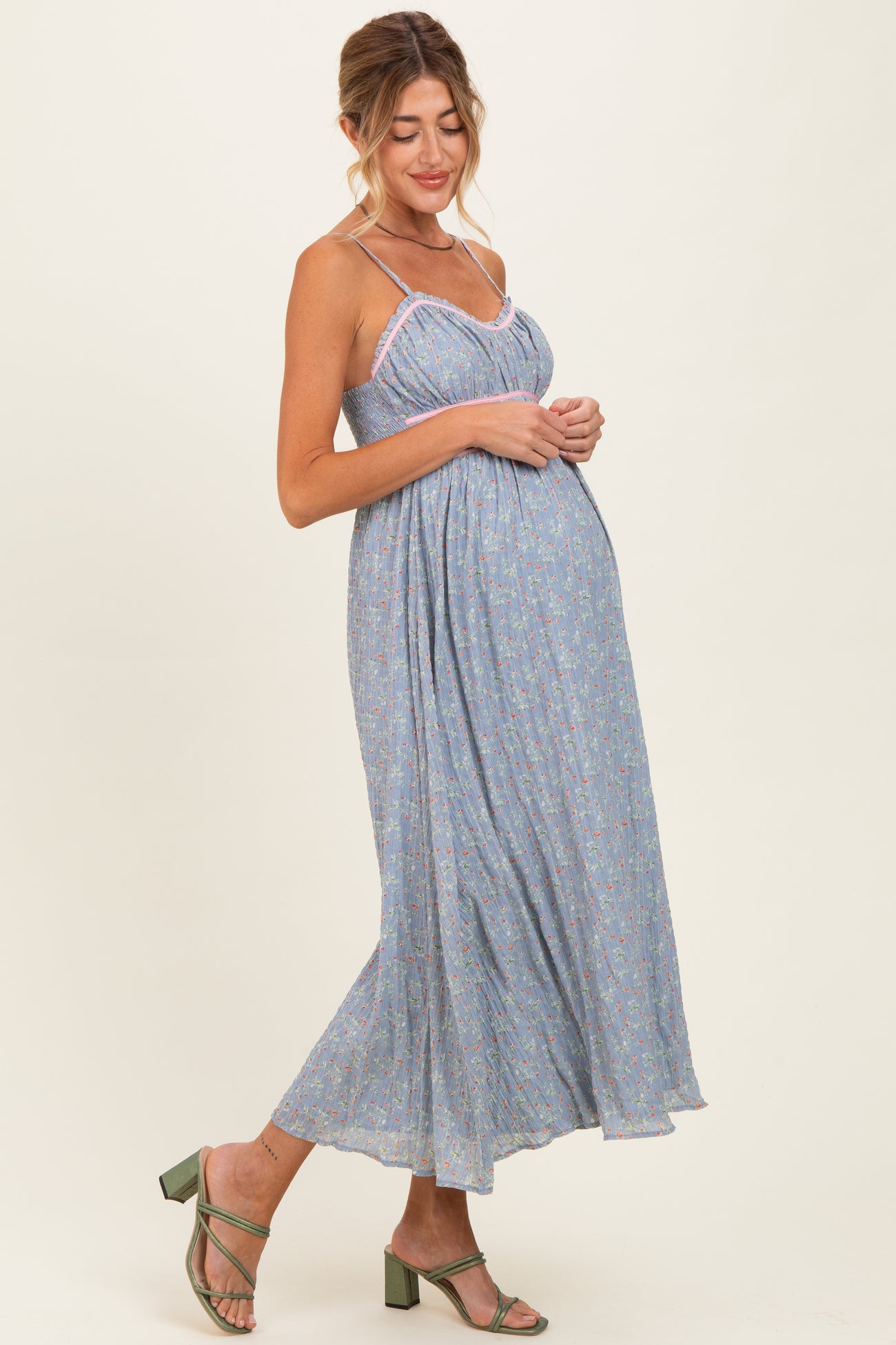 woman wearing a light blue floral maternity maxi dress with adjustable straps and a baby bump visible