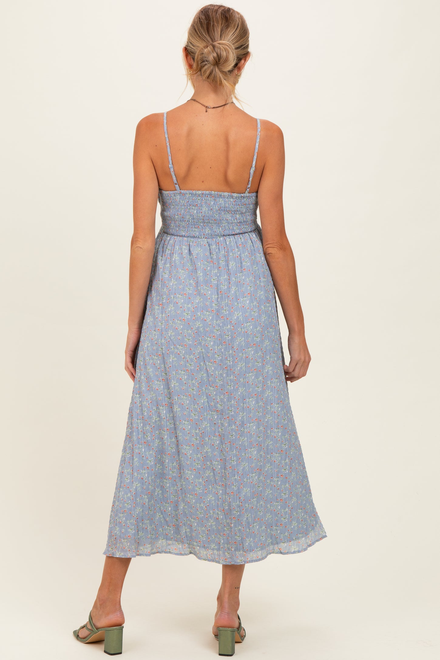 woman wearing a blue floral maternity maxi dress with adjustable straps and a smocked bodice, showing her back