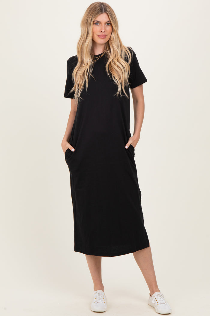 woman wearing a black short sleeve maxi dress with side pockets and white sneakers