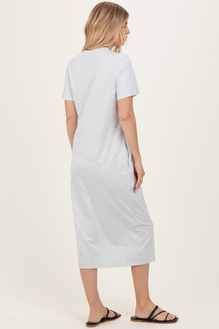 woman wearing a gray short sleeve midi dress, facing away from the camera, standing on a neutral background