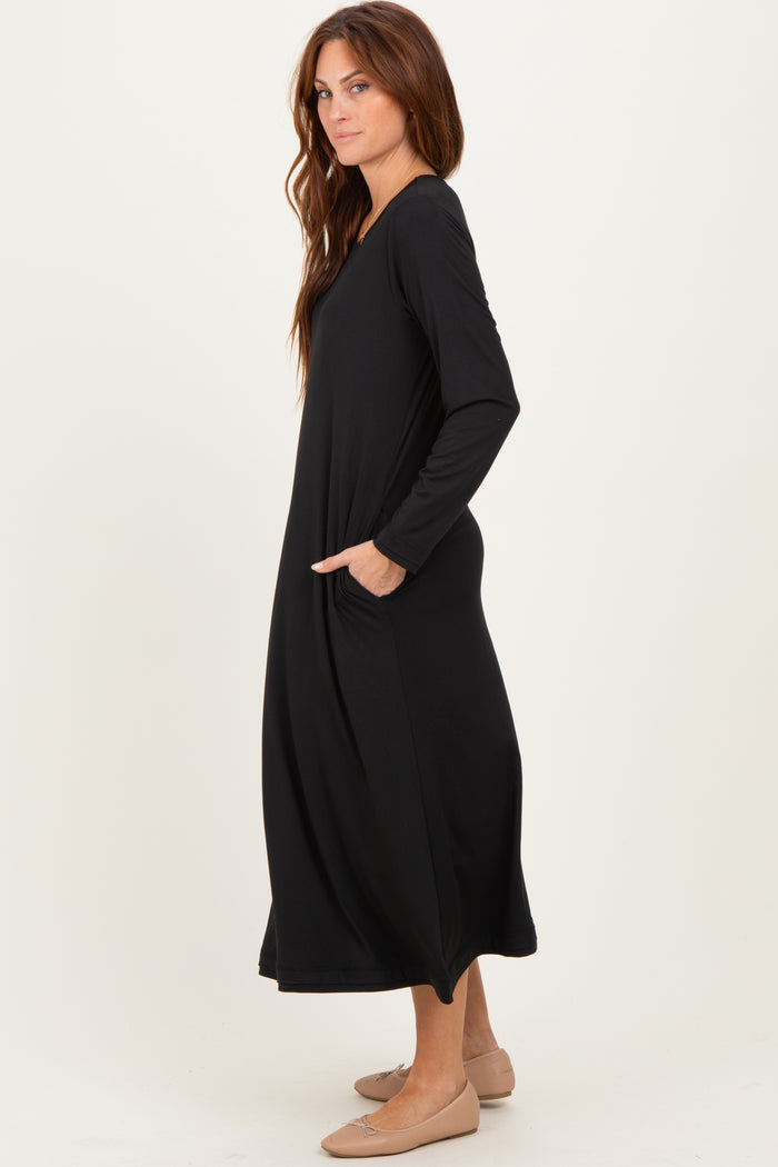 woman wearing a black long sleeve maxi dress with side pockets and a relaxed fit