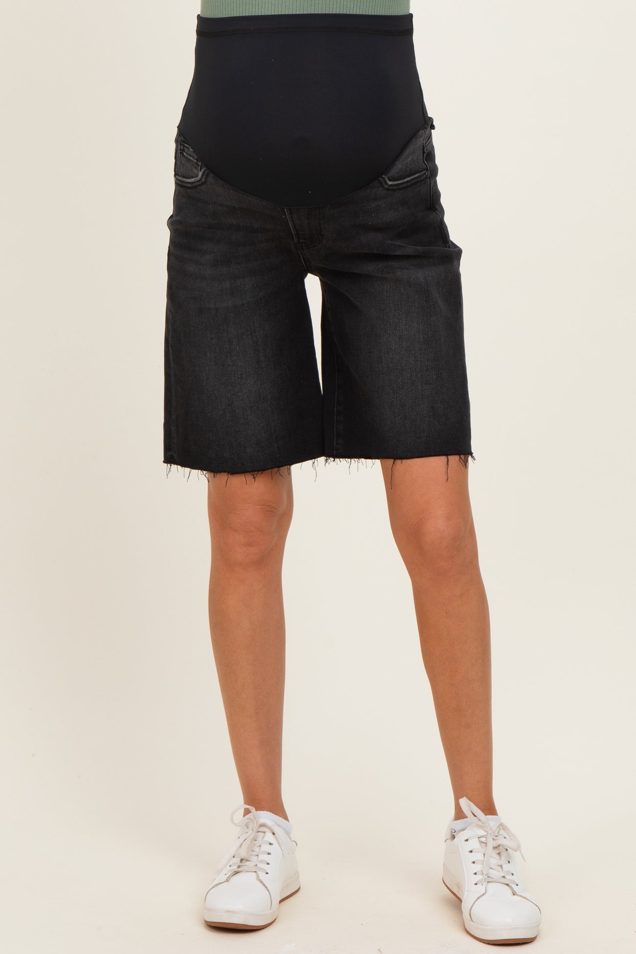 woman wearing black maternity denim shorts with a stretchy waistband and frayed hem, showcasing her baby bump