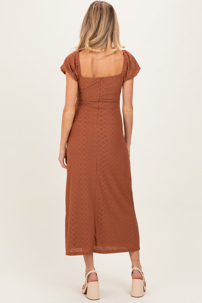 woman wearing a rust-colored midi maternity dress with short puff sleeves and a square back design