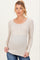 woman wearing a beige long sleeve maternity top with button details and a visible baby bump