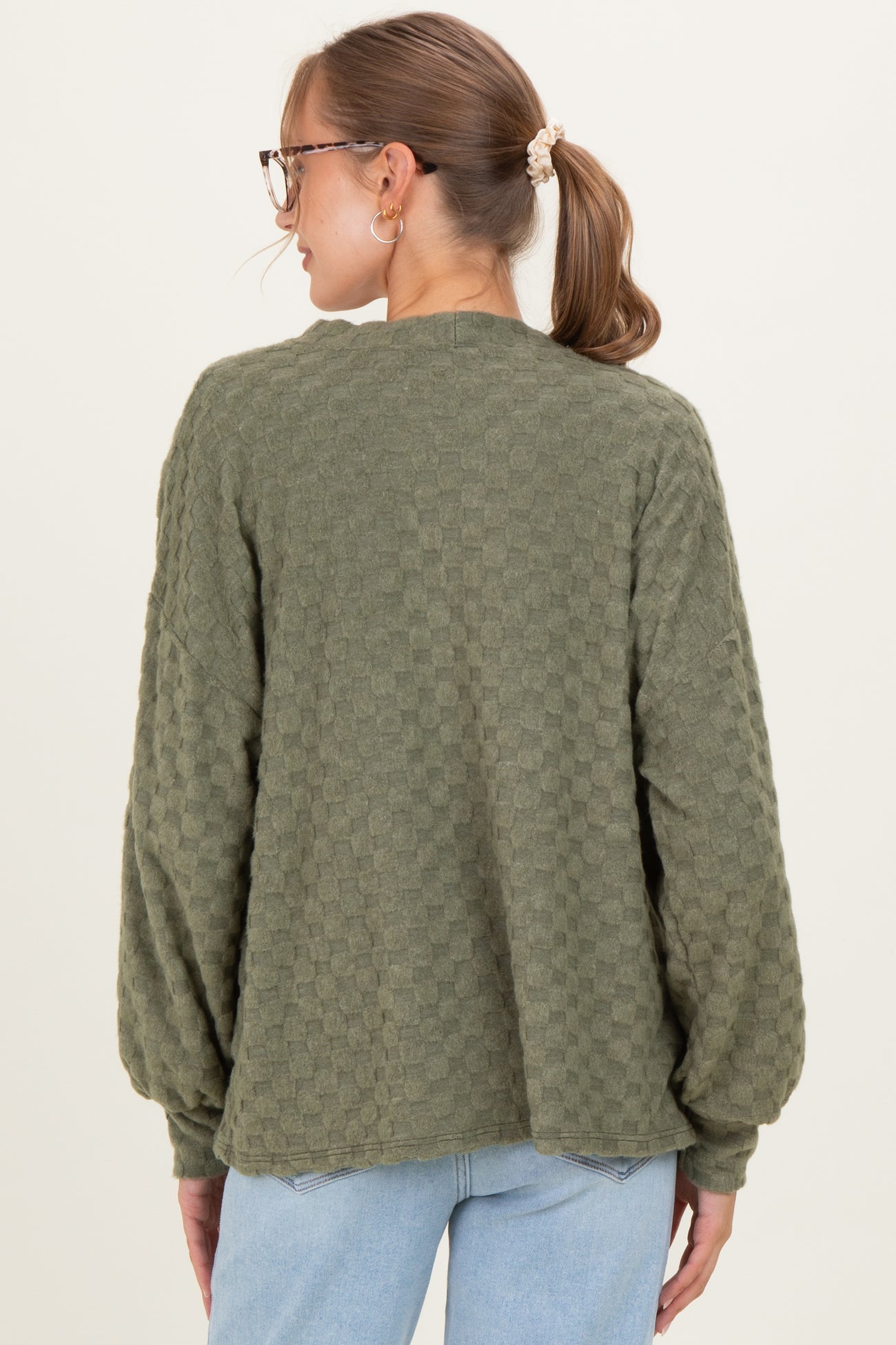 woman wearing a green textured long sleeve maternity sweater from the back with a relaxed fit
