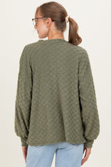 woman wearing a green textured long sleeve maternity sweater from the back with a relaxed fit