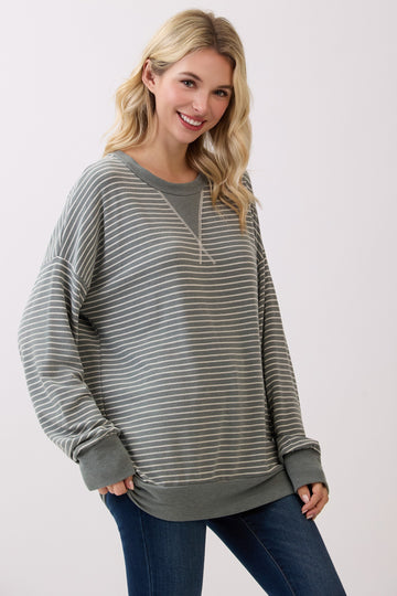 woman wearing a grey and white striped oversized sweatshirt with a rounded neckline and relaxed fit while smiling