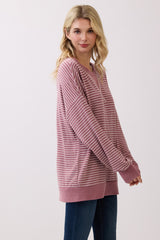 woman wearing a pink striped oversized sweatshirt with long sleeves and a relaxed fit