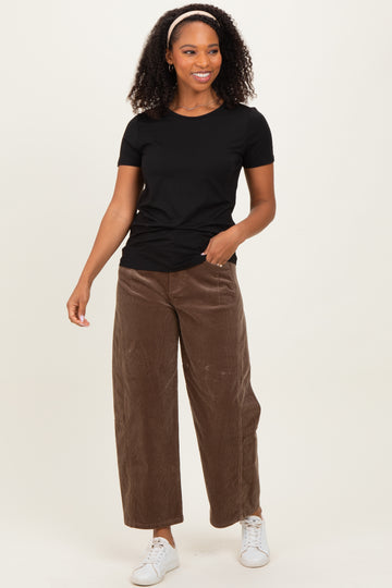 woman wearing a black short sleeve t-shirt and brown wide-leg corduroy pants with white sneakers