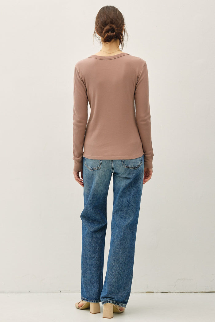 woman wearing a brown long sleeve top with a scoop neckline and relaxed fit paired with light blue wide-leg jeans