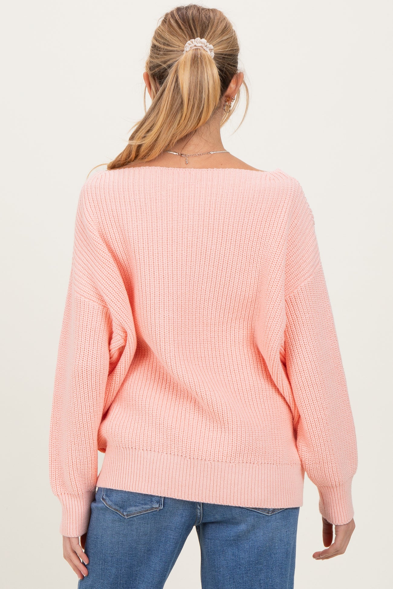 woman wearing a light pink oversized maternity sweater with a ribbed texture and relaxed fit