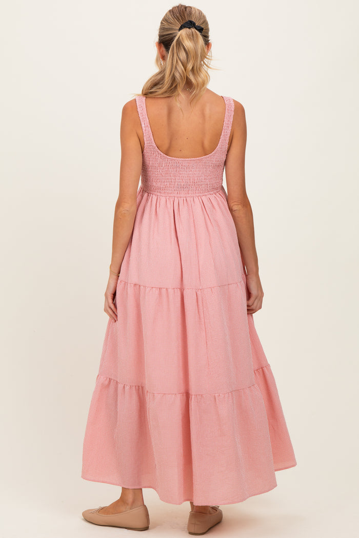 woman wearing a pink striped maternity maxi dress with a smocked bodice and tiered skirt, seen from the back