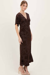 woman wearing a brown floral velvet maxi dress with a deep v-neck and short sleeves