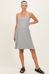 woman wearing a black and white striped maternity dress with a v-neckline and a flowy skirt, posing with one hand on her hip