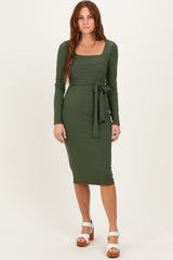 woman wearing a long sleeve olive green ribbed midi dress with a square neckline and a tied waist detail