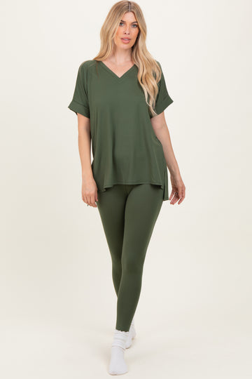 woman wearing an olive green oversized v-neck top and matching leggings, standing on white background