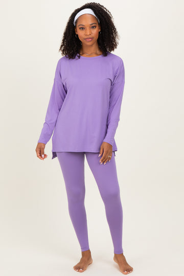 woman wearing a purple long sleeve top and matching leggings, with a headband in her hair