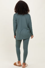 woman wearing a long sleeve teal tunic and matching leggings, seen from the back, paired with cozy slippers