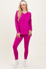 woman wearing a bright pink long sleeve top and matching leggings, standing on a neutral background