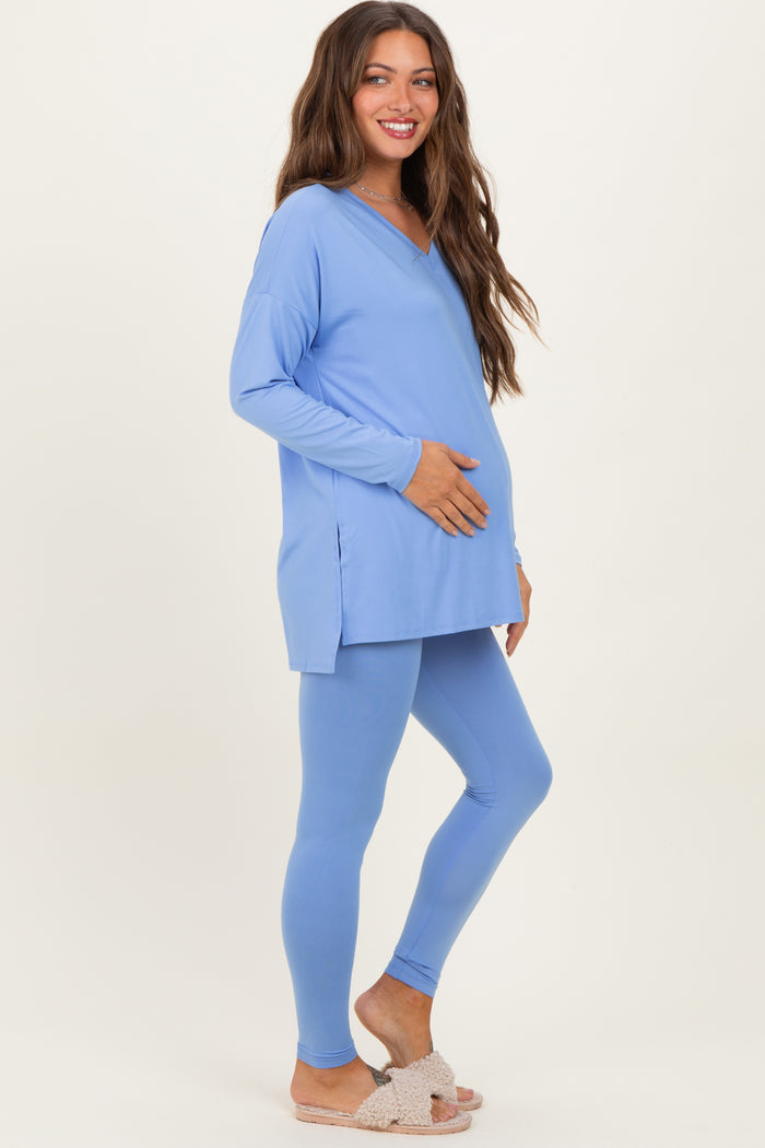 woman wearing a light blue maternity tunic and leggings, holding her baby bump