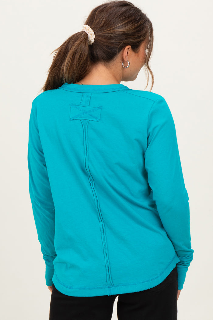 woman wearing a bright teal long sleeve maternity top with a stitching detail on the back