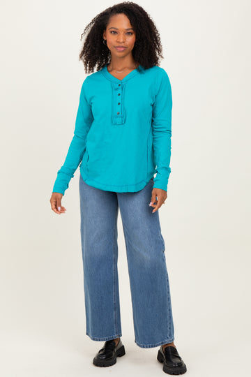 woman wearing a turquoise long sleeve henley top paired with wide leg jeans and black loafers