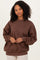 woman wearing a brown oversized sweatshirt with long sleeves and a relaxed fit