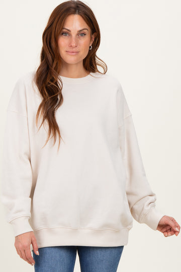 woman wearing a cream oversized sweatshirt with relaxed fit and long sleeves, paired with blue jeans