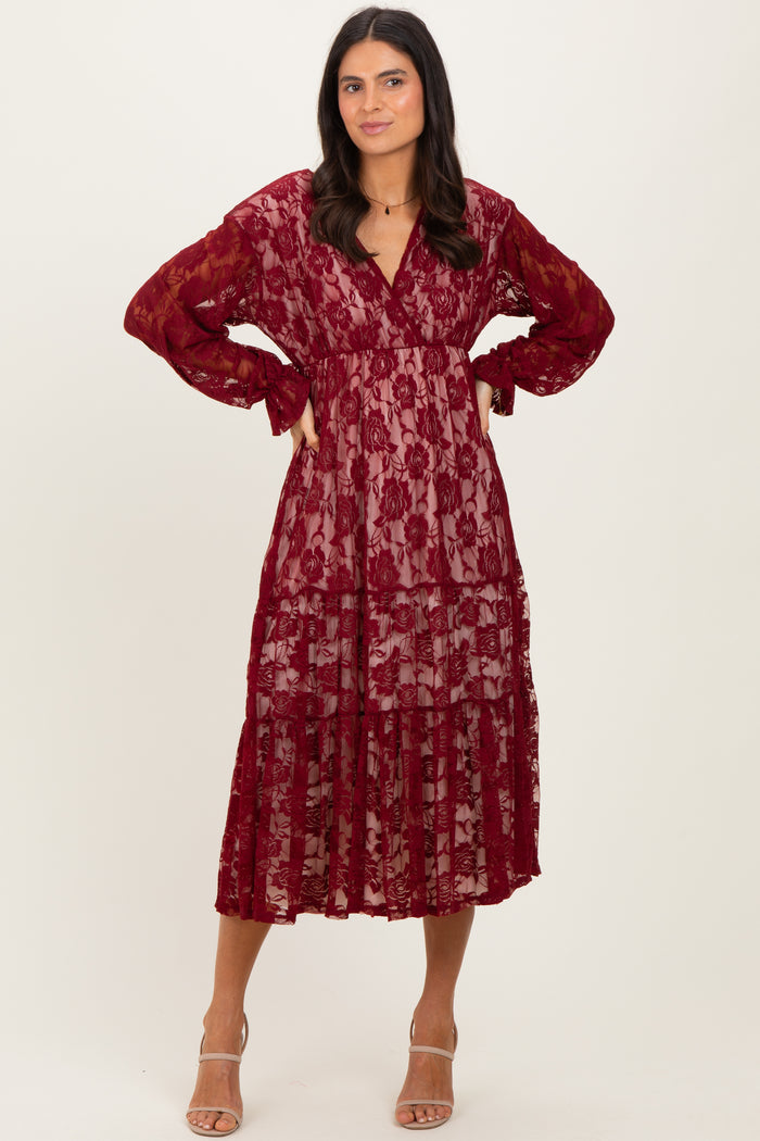 woman wearing a burgundy lace tiered maxi dress with long sleeves and a v-neckline