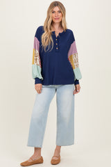 woman wearing a navy ribbed henley top with multicolored balloon sleeves and light blue wide-leg jeans