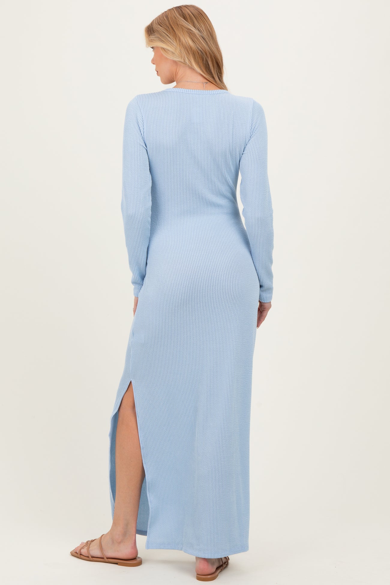 woman wearing a light blue long sleeve maternity dress with a side slit, showing a relaxed fit from the back