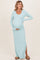 woman wearing a light blue ribbed maternity maxi dress with a side slit and holding her baby bump
