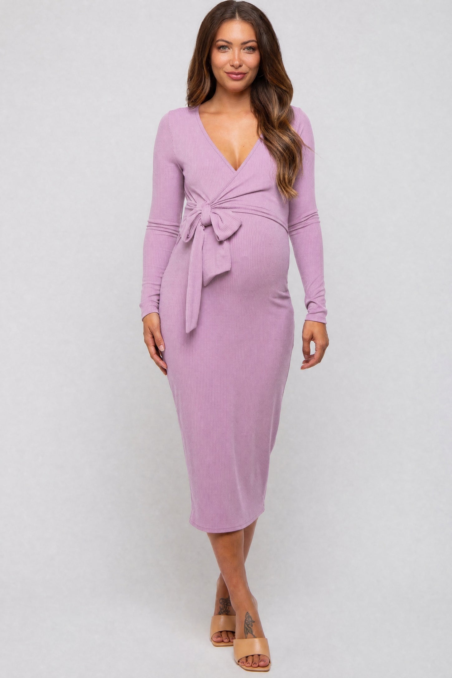 woman wearing a lavender long sleeve maternity dress with a tie waist and a visible baby bump