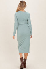 woman wearing a fitted green ribbed maternity dress with long sleeves, showing a stylish back view