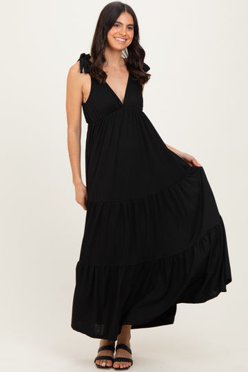 woman wearing a black tiered maxi dress with tie straps and a deep v-neckline