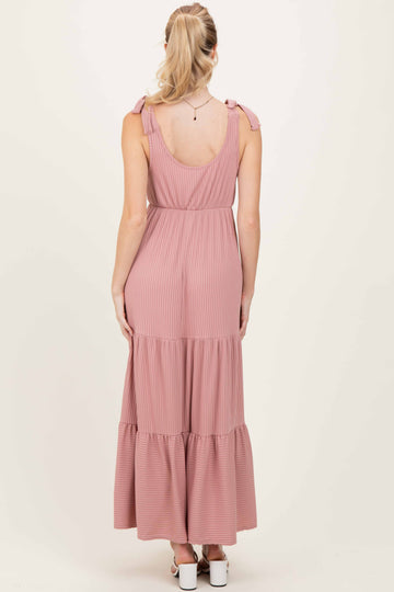 woman wearing a light pink striped maxi dress with adjustable tie straps and tiered ruffle hem