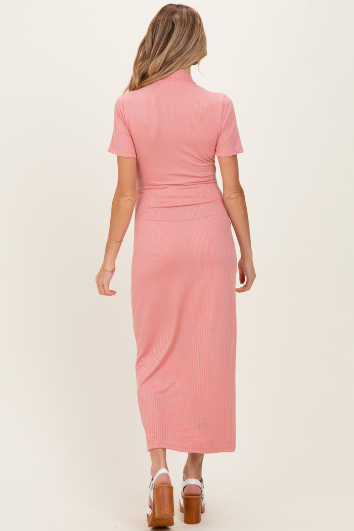 woman wearing a dusty pink ribbed maternity dress with short sleeves and a fitted waist, showing her baby bump