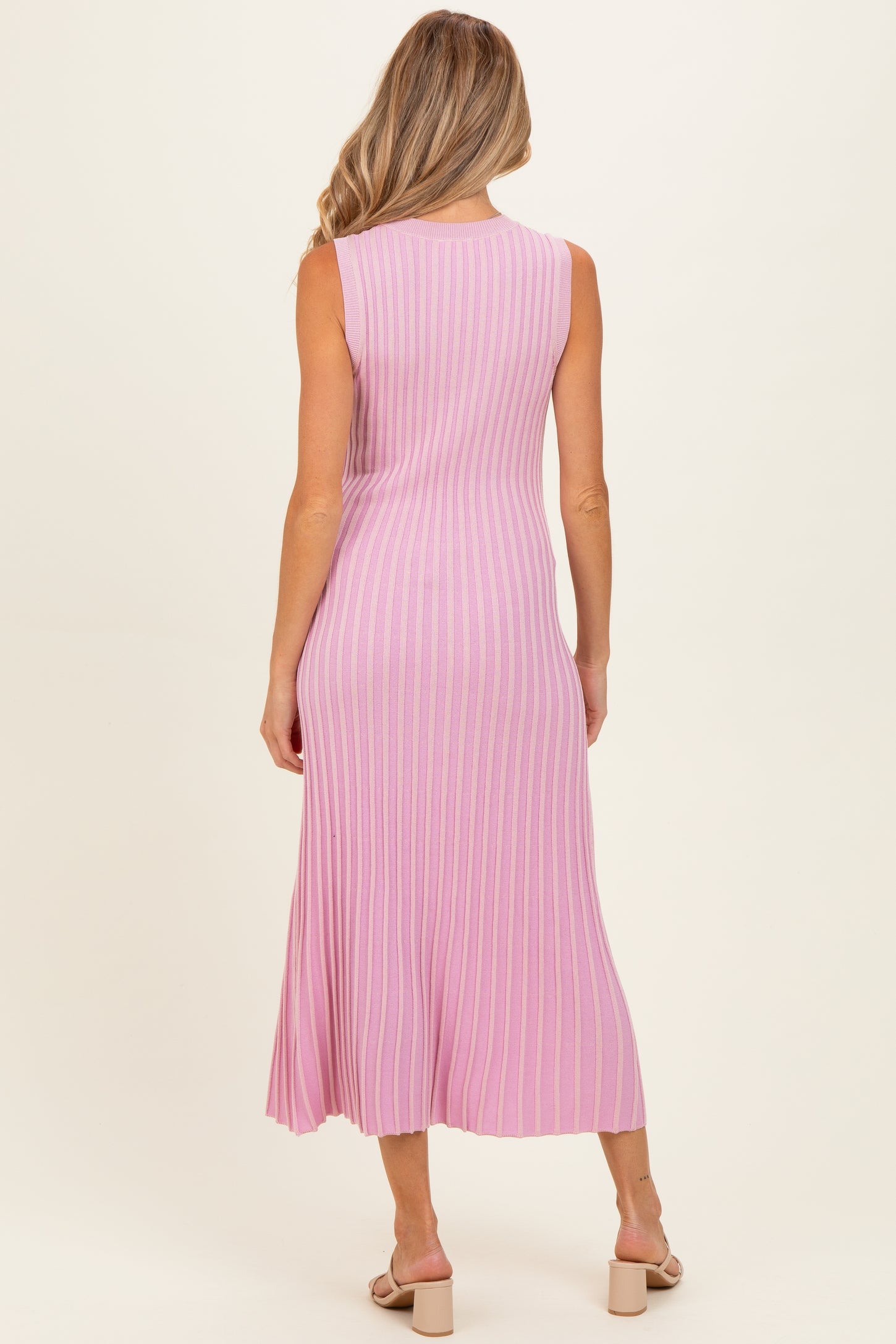 woman wearing a pink ribbed midi maternity dress, showing the back view and featuring a fitted style
