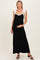 woman wearing a black maternity maxi dress with white tie straps and holding her baby bump