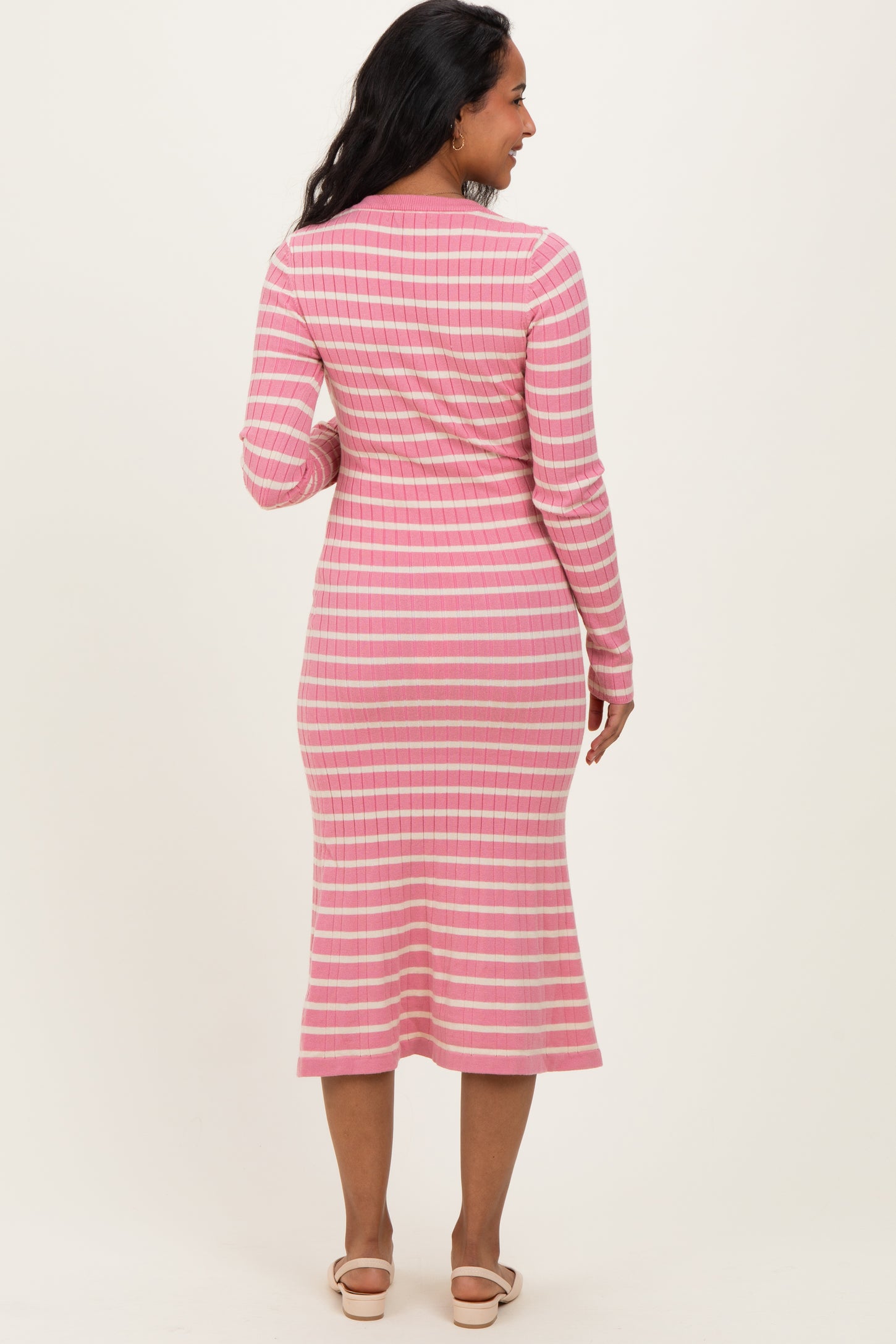 woman wearing a pink striped long sleeve maternity dress, showing a fitted silhouette and midi-length skirt from the back