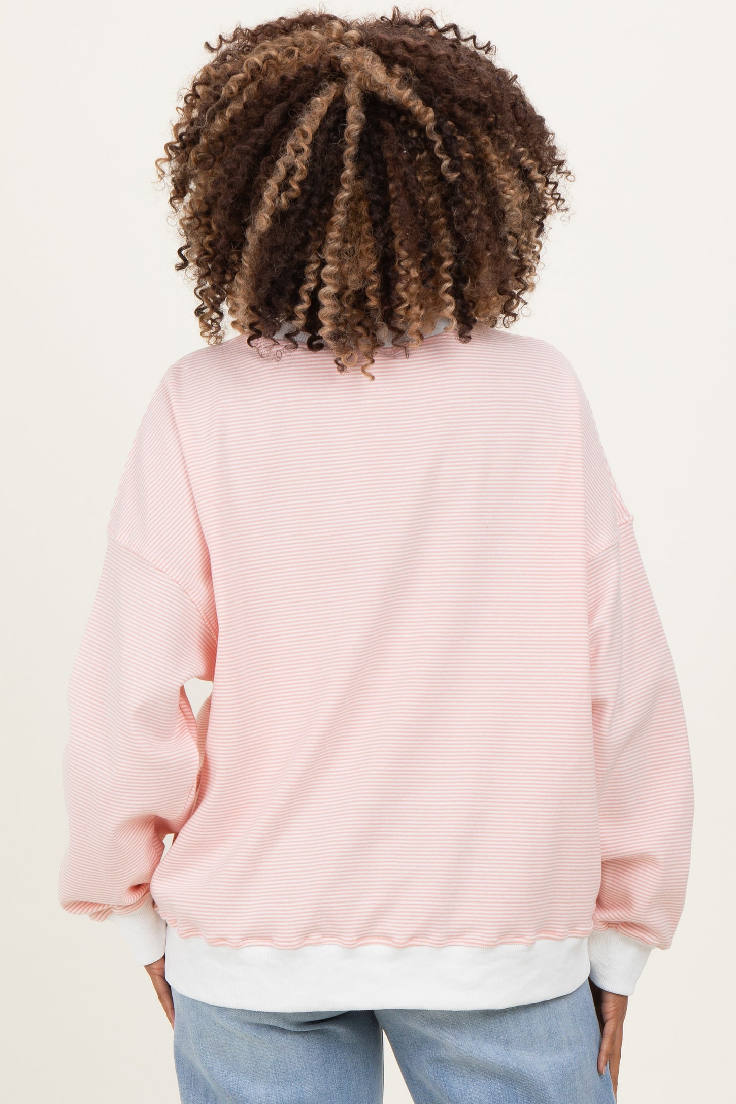 woman wearing a pink striped maternity sweatshirt with balloon sleeves and a white hem, viewed from the back