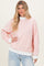 woman wearing a light pink striped oversized sweatshirt with white cuffs and hem, standing against a neutral background